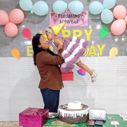 Meenakshi Ma'am lifting a child at a birthday celebration