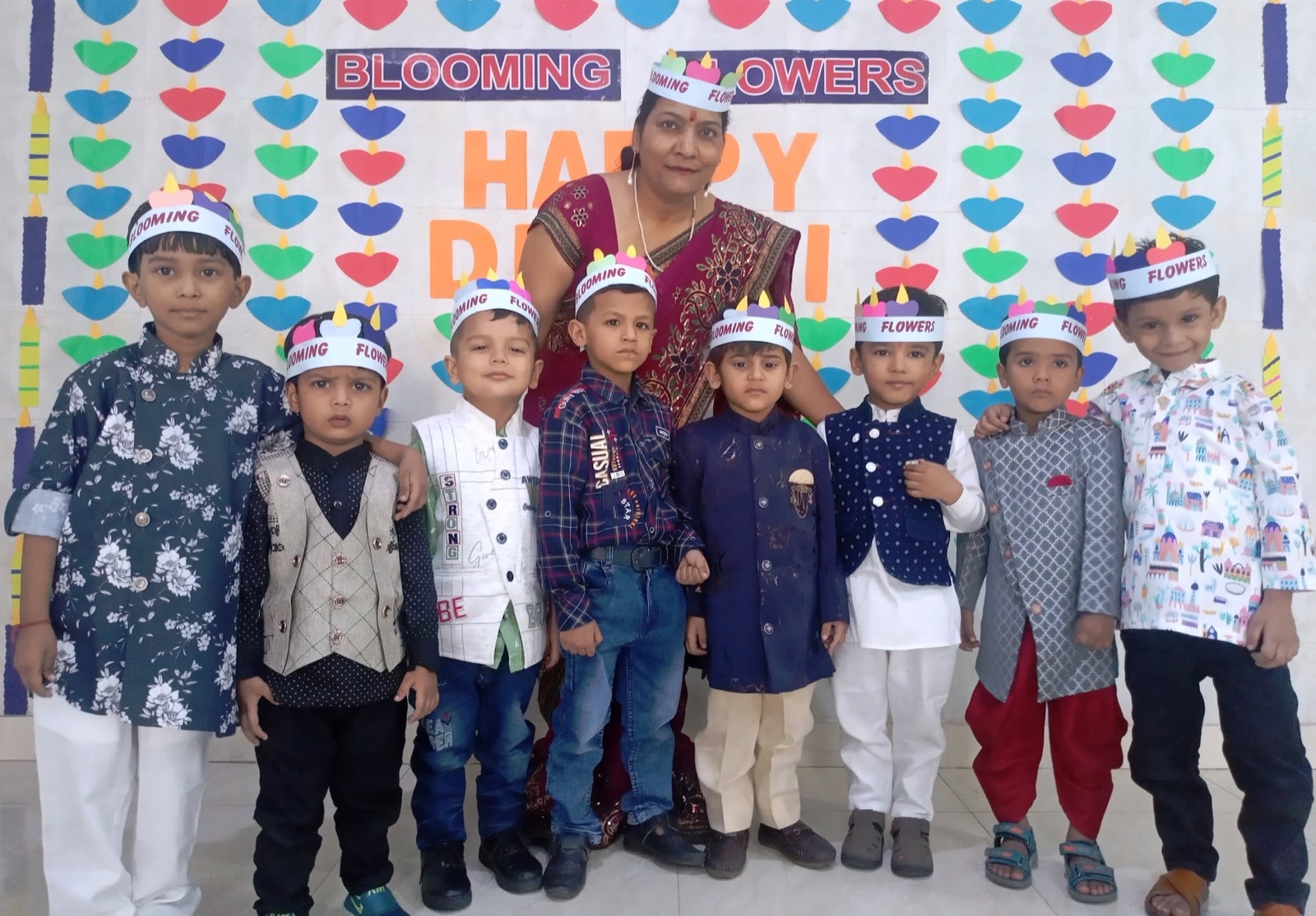 Children in festive outfits with their teacher in front of a Happy Diwali board